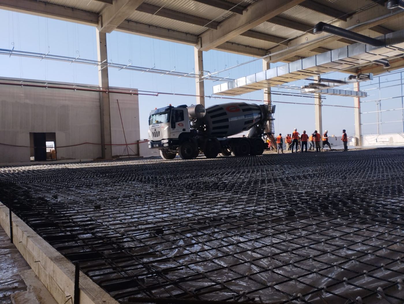 Mixer truck and crew working on a large mesh-reinforced slab